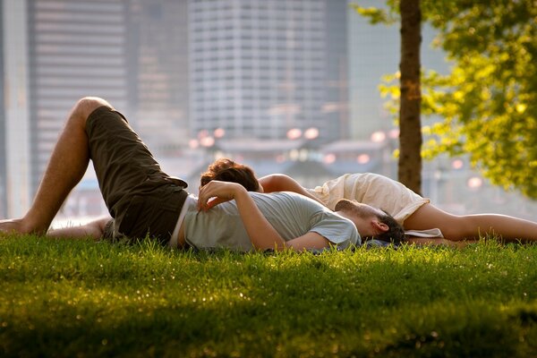 Влюбленная пара валяется на траве в парке большого города