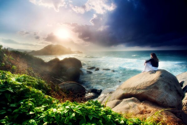 Девушка сидящая на камне на берегу моря