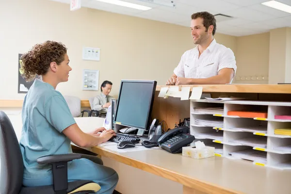 Медсестра и пациент, беседуя на стойке регистрации Стоковое Фото
