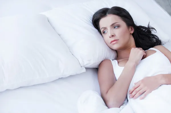 Женщина, лежа на кровати и глядя на пустую подушку Стоковое Фото