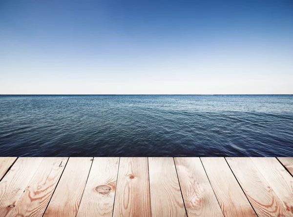Деревянный пирс на фоне синего неба и моря — стоковое фото