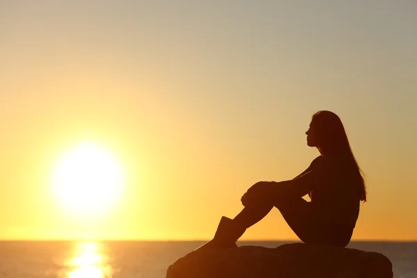 Силуэт женщина, наблюдая за солнцем в закат — стоковое фото