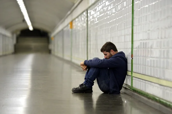 Молодой человек потерял в депрессии, сидя на земле улица метро тоннеля Лицензионные Стоковые Фото