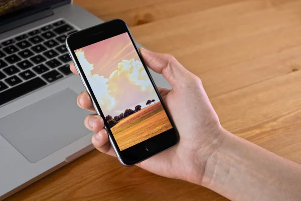 Iphone 6 держать в руке с Macbook — стоковое фото