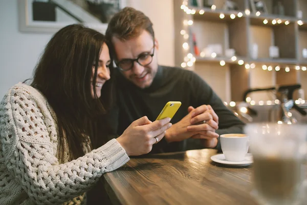 Молодая пара в кафе, сидящем со смартфоном и кофе — стоковое фото