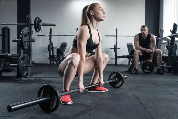 Женщина делает силовые тренировки, пока человек сидит Стоковое Фото