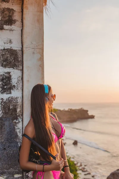 Side View Attractive Girl Headphones Pink Bikini Leaning Wall Looking — стоковое фото