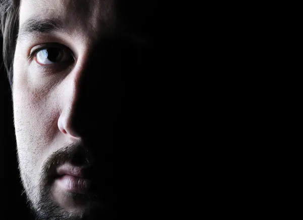 Low-key portrait - half face - sad and angry looking man — стоковое фото