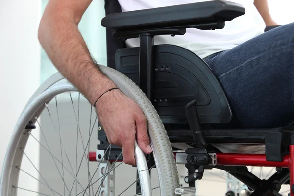 Крупным планом мужской руки на колесе его инвалидной коляски — стоковое фото