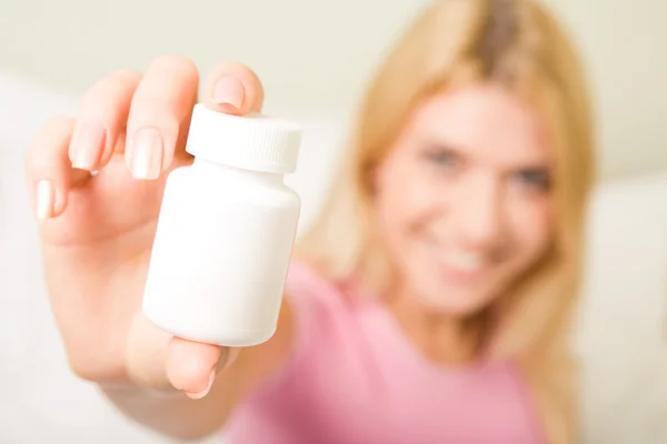 Женской руки, держащей бутылку пластиковых таблеток, содержащих витамины — стоковое фото