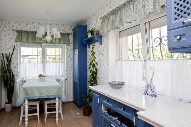Прованский стиль в оформлении интерьера бело-голубой кухни дополняют обои с мелкими цветами