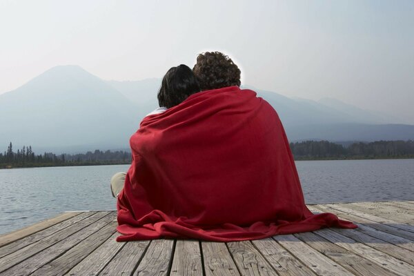 Двое влюбленных на причале под красным одеялом