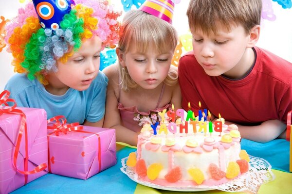 три ребенка задувают свечи на торте