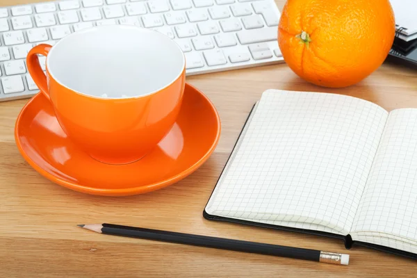 Чашка кофе, оранжевые плоды и офисные принадлежности — стоковое фото