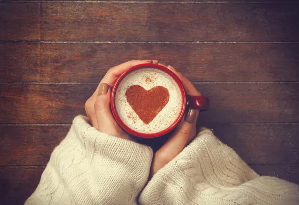 Женщина держит чашку горячего кофе, с формы сердца — стоковое фото