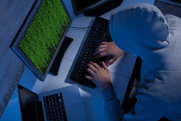 Хакер в куртка с капюшоном, с помощью компьютера в таблице — стоковое фото