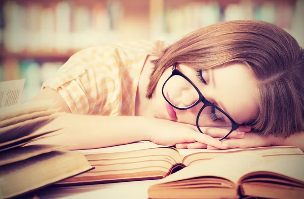 Устал студент девушка в очках спать на книгах в библиотеке Лицензионные Стоковые Фото