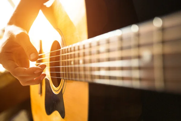 Рука играет на акустической гитаре — стоковое фото