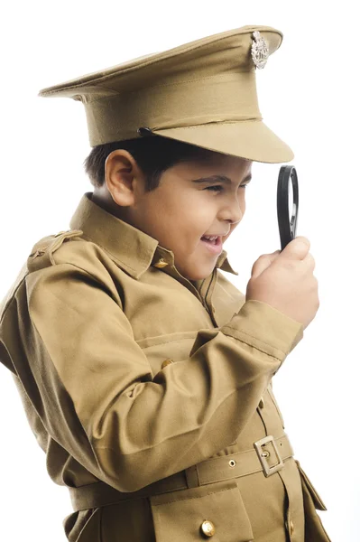 Крупный Мальчик одет в милицейской форме, смотрит через увеличительное стекло — стоковое фото