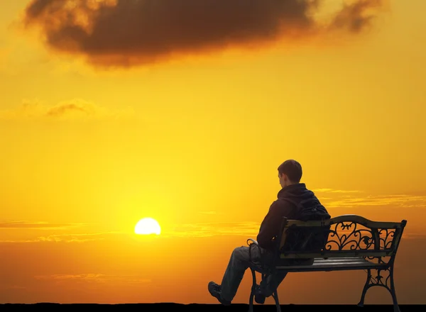 Одинокий человек сидит на закате — стоковое фото