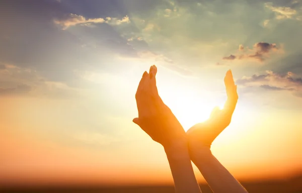 Руки, держа на солнце на рассвете — стоковое фото