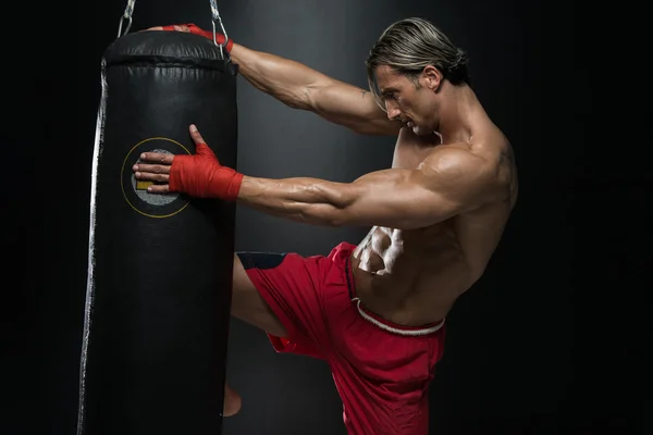 Зрелый человек, осуществляющих мешок бокс в студии — стоковое фото