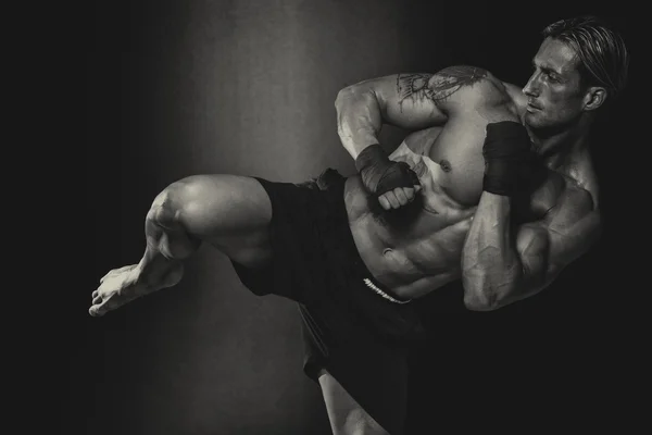 Боец ММА, практикуя некоторые ногами с боксерской грушей — стоковое фото