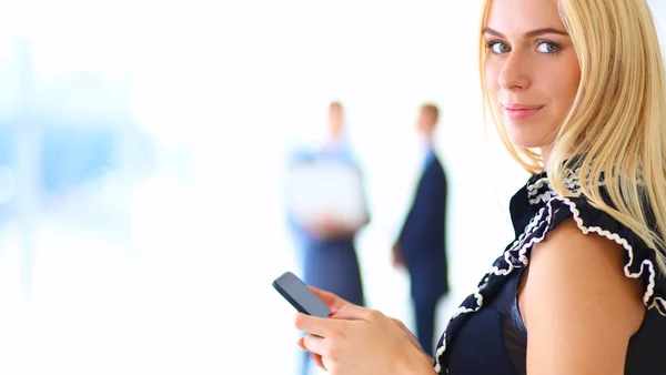 Красивый бизнес-леди с помощью сотового телефона, стоя в офисе — стоковое фото