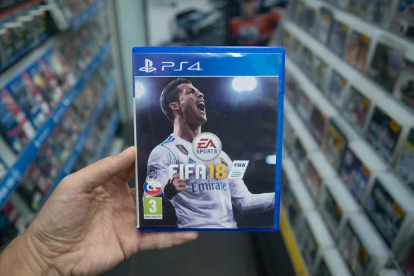 Человек, держащий ФИФА 18 Видеоигровые консоли Sony Playstation 4 в магазине — стоковое фото