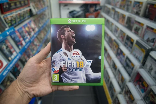 Человек, держащий 18 ФИФА видеоигры на Microsoft Xbox консолей в магазине — стоковое фото