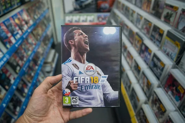 Человек, держащий 18 ФИФА видеоигры на ПК в магазине — стоковое фото