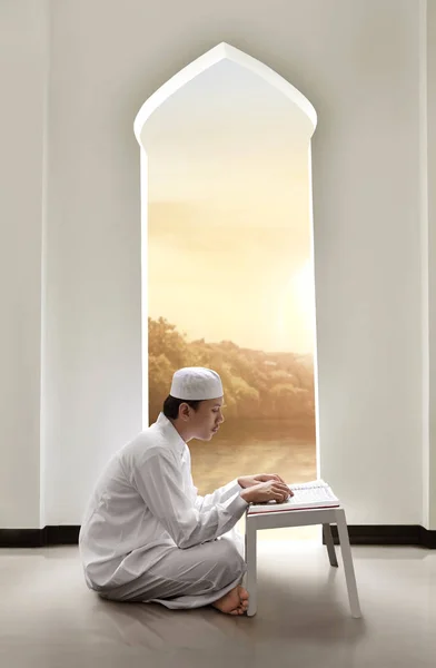 Молодой человек азиатских мусульман с крышкой, чтение священной книги Корана — стоковое фото