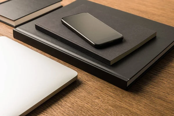Крупным планом вид ноутбука, кучу черных ноутбуков и смартфонов на деревянные настольные — стоковое фото