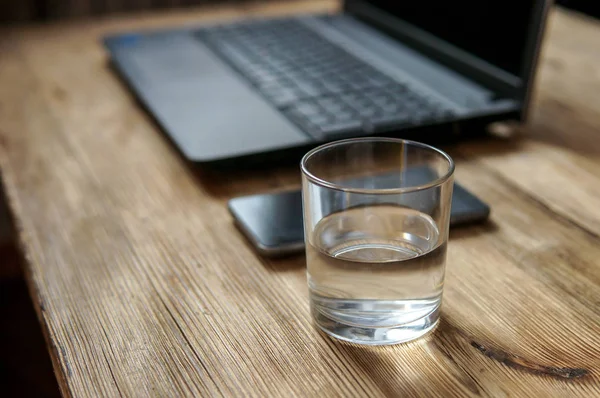 Рабочий процесс - изображения смартфона, стакан воды, ноутбук. выборочный фокус на стакан воды — стоковое фото