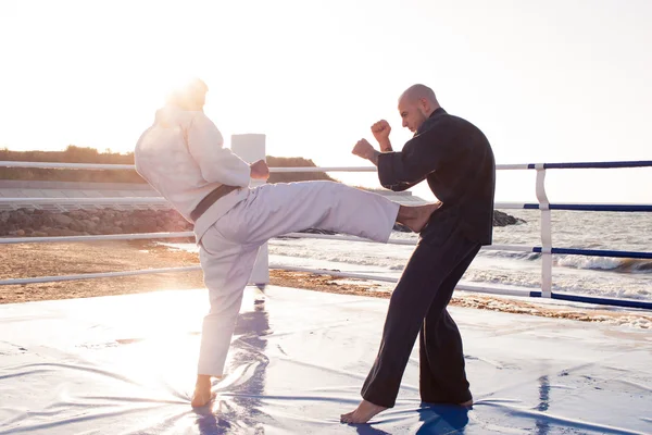 Два профессиональных мужских каратэ бойцов борются на пляже бокс кольцо — стоковое фото