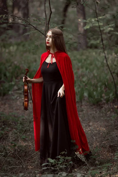 Attractive Mystic Woman Red Cloak Holding Violin Dark Forest — стоковое фото