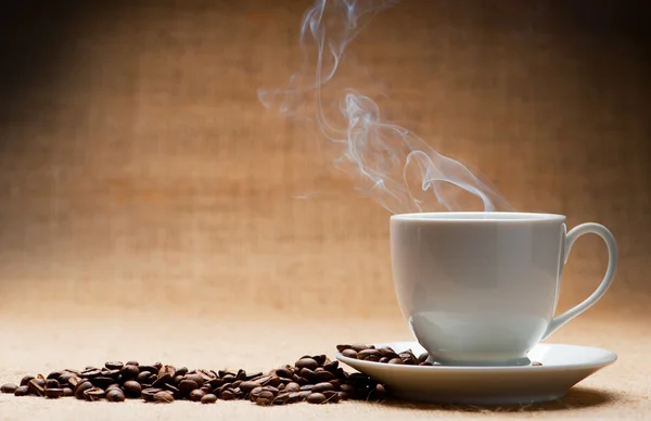 Чашка горячего кофе о пароме и зернах кофе на гранже — стоковое фото