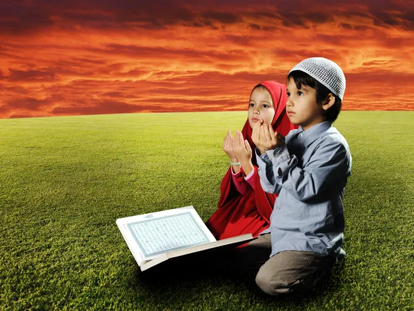 Двое детей мусульман, сидя на лугу в Рамадан и чтения Корана и пра — стоковое фото